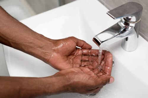 person washing hands under faucet with low water pressure